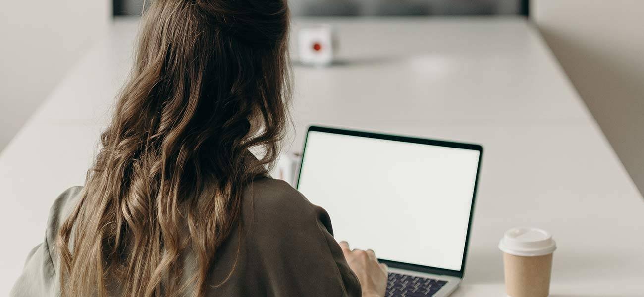 Woman typing on laptop at a table, emphasizing email marketing strategies and engagement.
