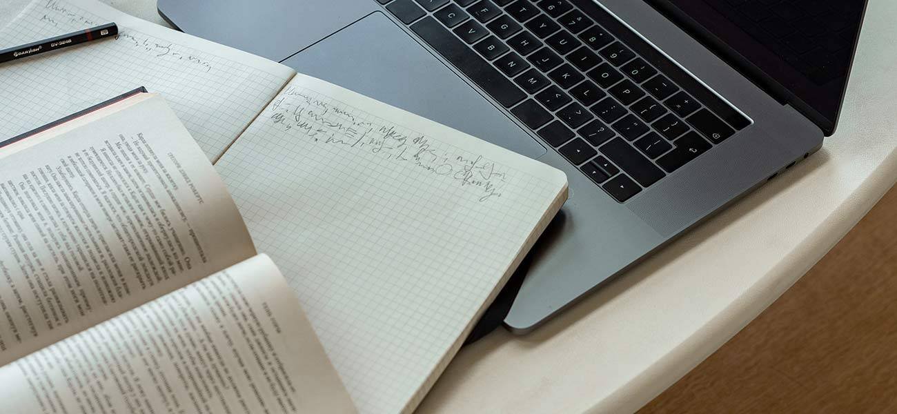 Laptop on a table with open notebooks and a pencil, illustrating email marketing strategy planning and list segmentation concepts.