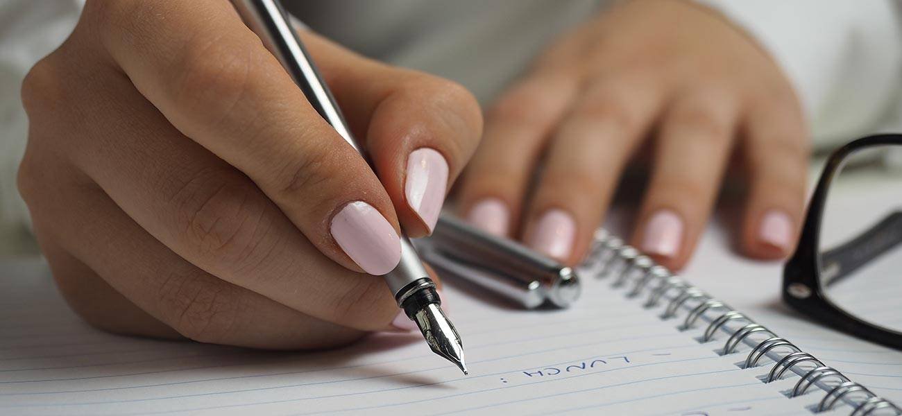 Hand writing in a notebook with a fountain pen, emphasizing the importance of note-taking for effective email marketing strategies and subscriber list hygiene.