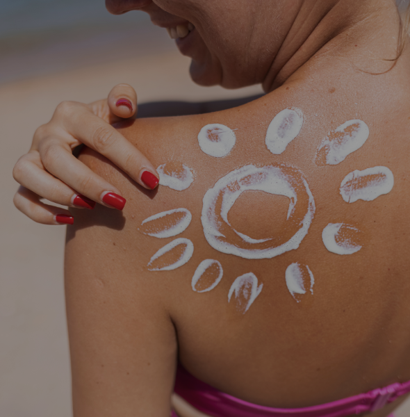Woman applying sunscreen with a sun design on her shoulder, promoting skin protection and tanning bar services.
