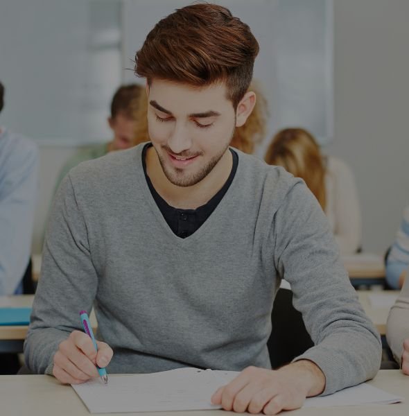 Smiling student writing notes during a test preparation session in a classroom setting, reflecting engagement and focus on academic success. Smiling student writing notes during a test preparation session in a classroom setting, reflecting engagement and focus on academic success.